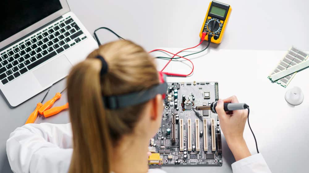 high-angle-female-technician-with-soldering-iron-electronics-motherboard-min
